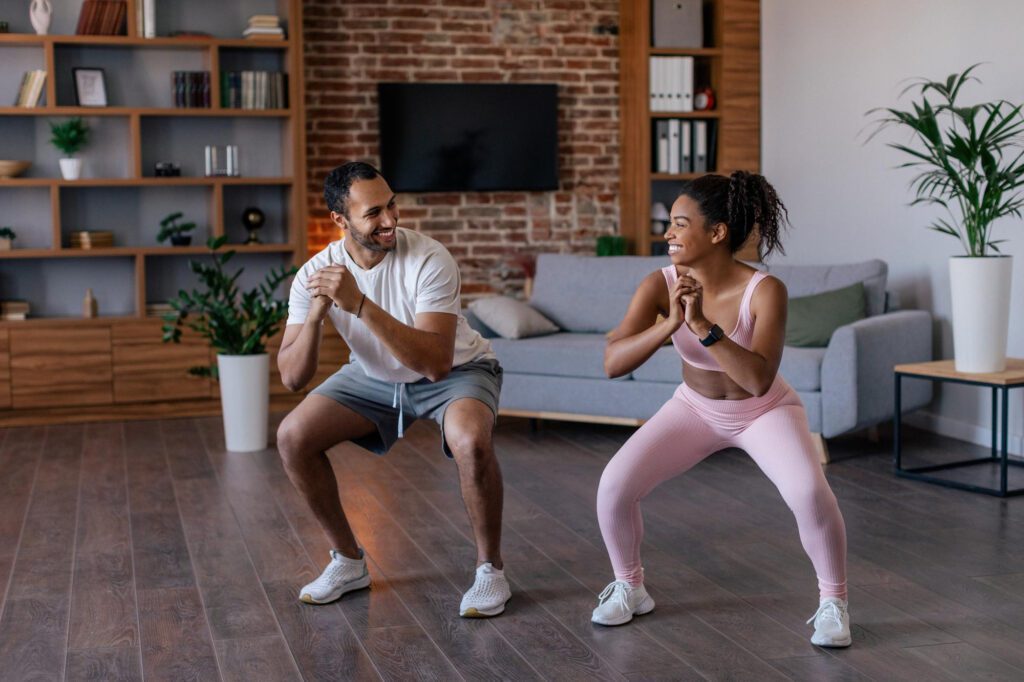 cheerful-young-african-american-husband-wife-sportswear-doing-squat-exercises 