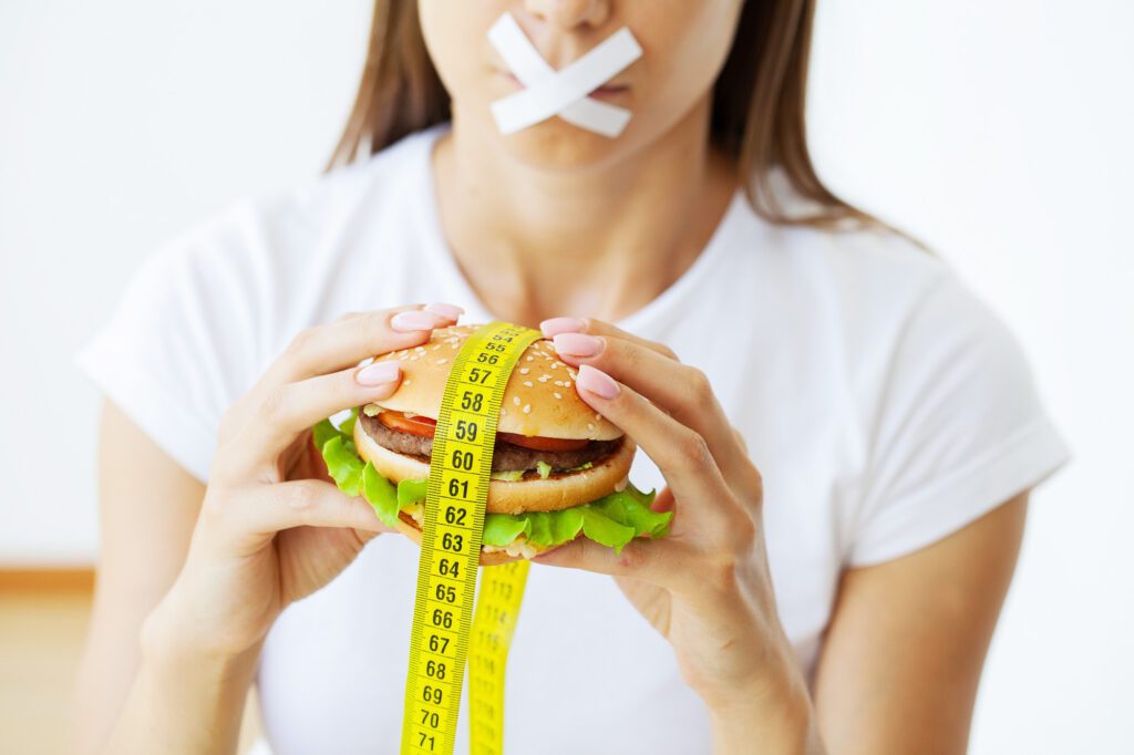 concept-diet-woman-with-sealed-mouth-keeps-greasy-burger- 