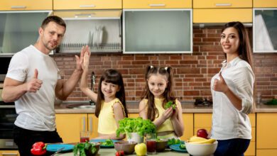 portrait happy family mom dad two daughters cooking salads kitchen home 2
