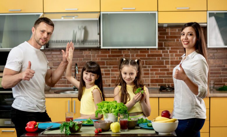 portrait happy family mom dad two daughters cooking salads kitchen home 2