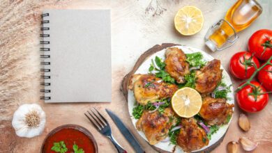 top view chicken sauce oil tomatoes garlic lemon chicken with herbs fork knife notebook