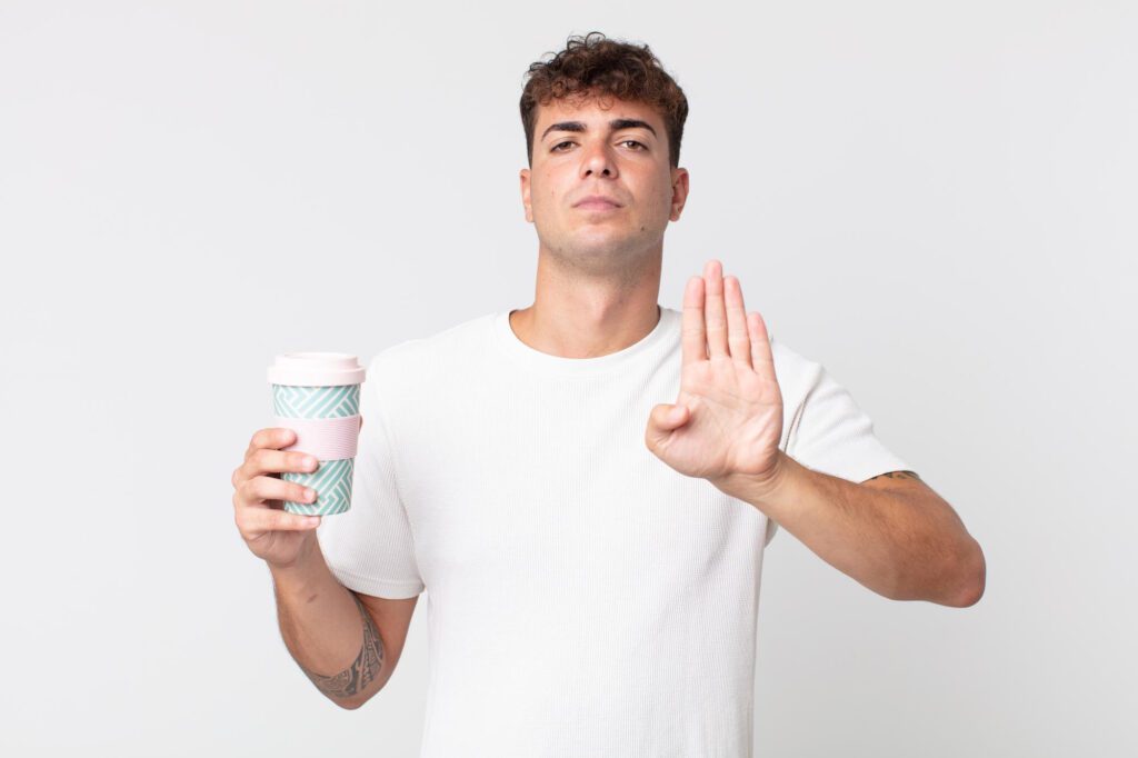 young-handsome-man-looking-serious-showing-open-palm-making-stop-gesture-holding-take-away-coffee 