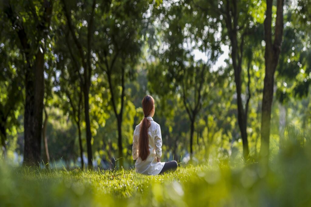 Woman relaxingly practicing meditation in the forest to attain h