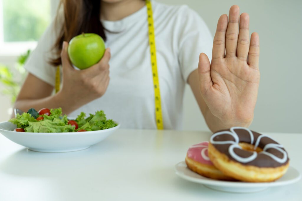 women reject junk food or unhealthy foods such as doughnuts and choose healthy foods such as green apples and salads concept of fasting and good health (2)