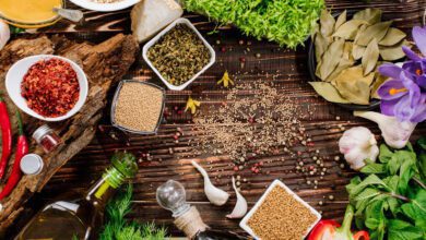 Assortment of fresh and dried herbs, spices, and vegetables spread across a rustic wooden background, highlighting the essentials of an anti inflammatory diet