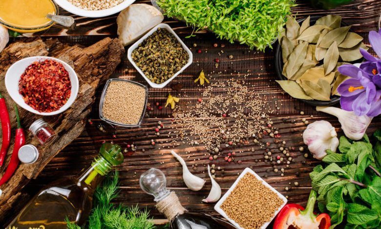 Assortment of fresh and dried herbs, spices, and vegetables spread across a rustic wooden background, highlighting the essentials of an anti inflammatory diet