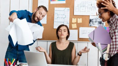 Colleagues debating over drawings while a woman practices meditation for stress relief in the workplace