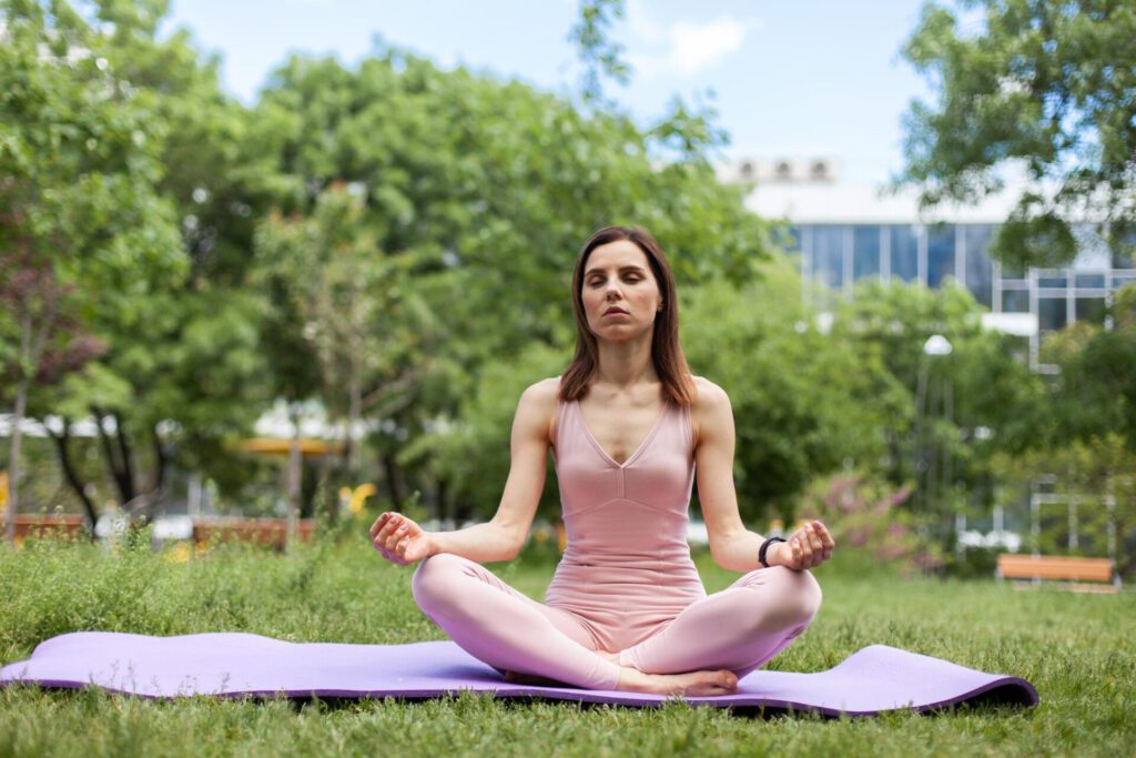 beautiful yogi woman meditating while sitting mat park