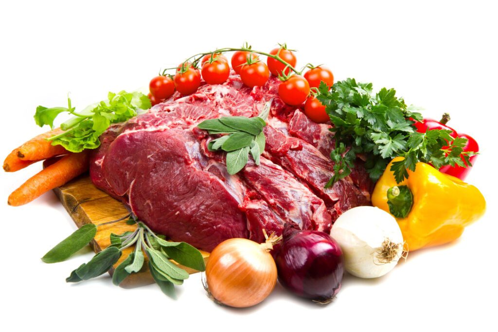 huge red meat chunk with vegetables isolated white table