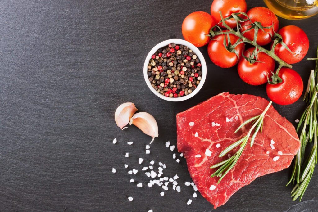 raw steak with cooking ingridients black slate background