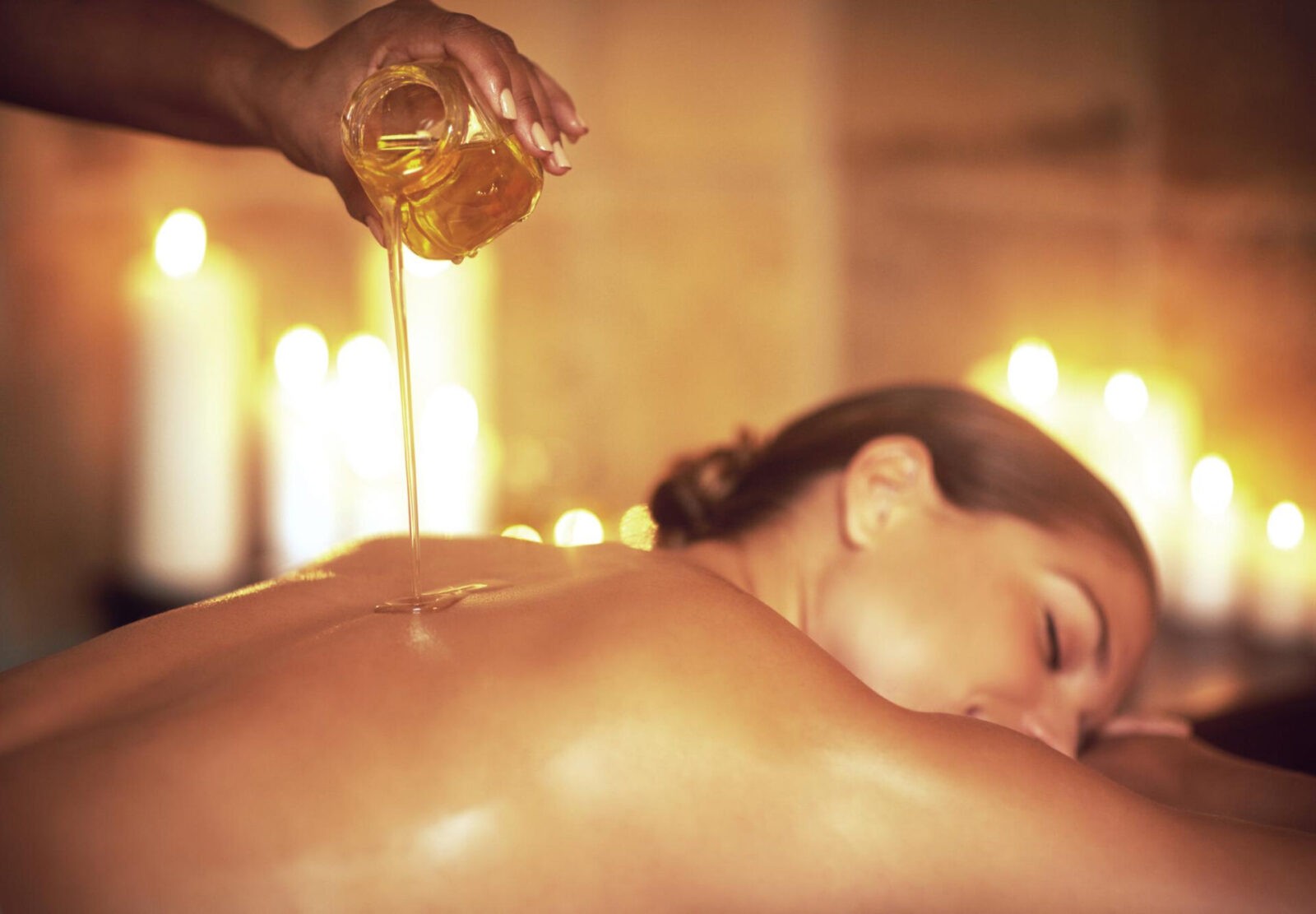 where stress ends relaxation begins shot masseuse pouring oil womans back before her massage